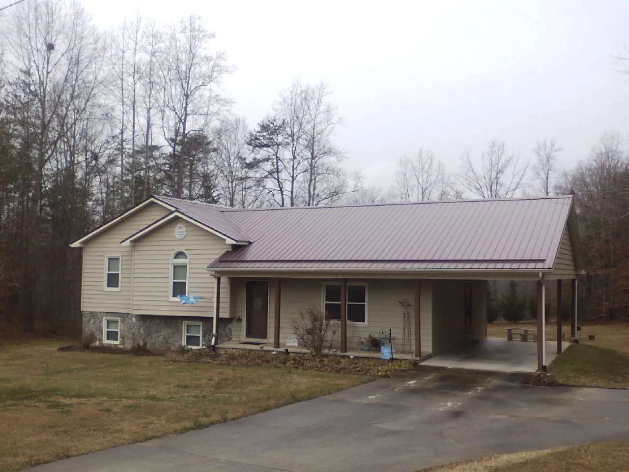Burgundy metal roof on a tan split level home with an attached carport in Blairs