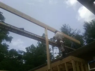 Carpenter setting a ridge beam over a new addition frame — Ice Dam Removal by Roofing Brothers in Blairs