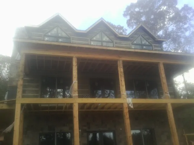 Dormers and porch framing on a large log home under construction — Roof Coating work by our crew in Blairs