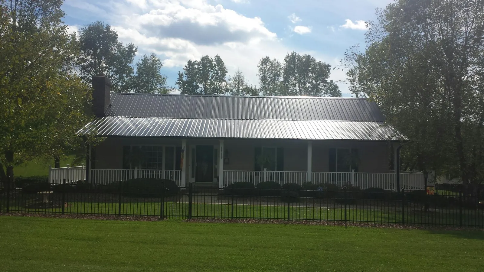 Gray metal roof on a brick ranch with a full width front porch — Gutter Guard Installation work by our crew in Blairs