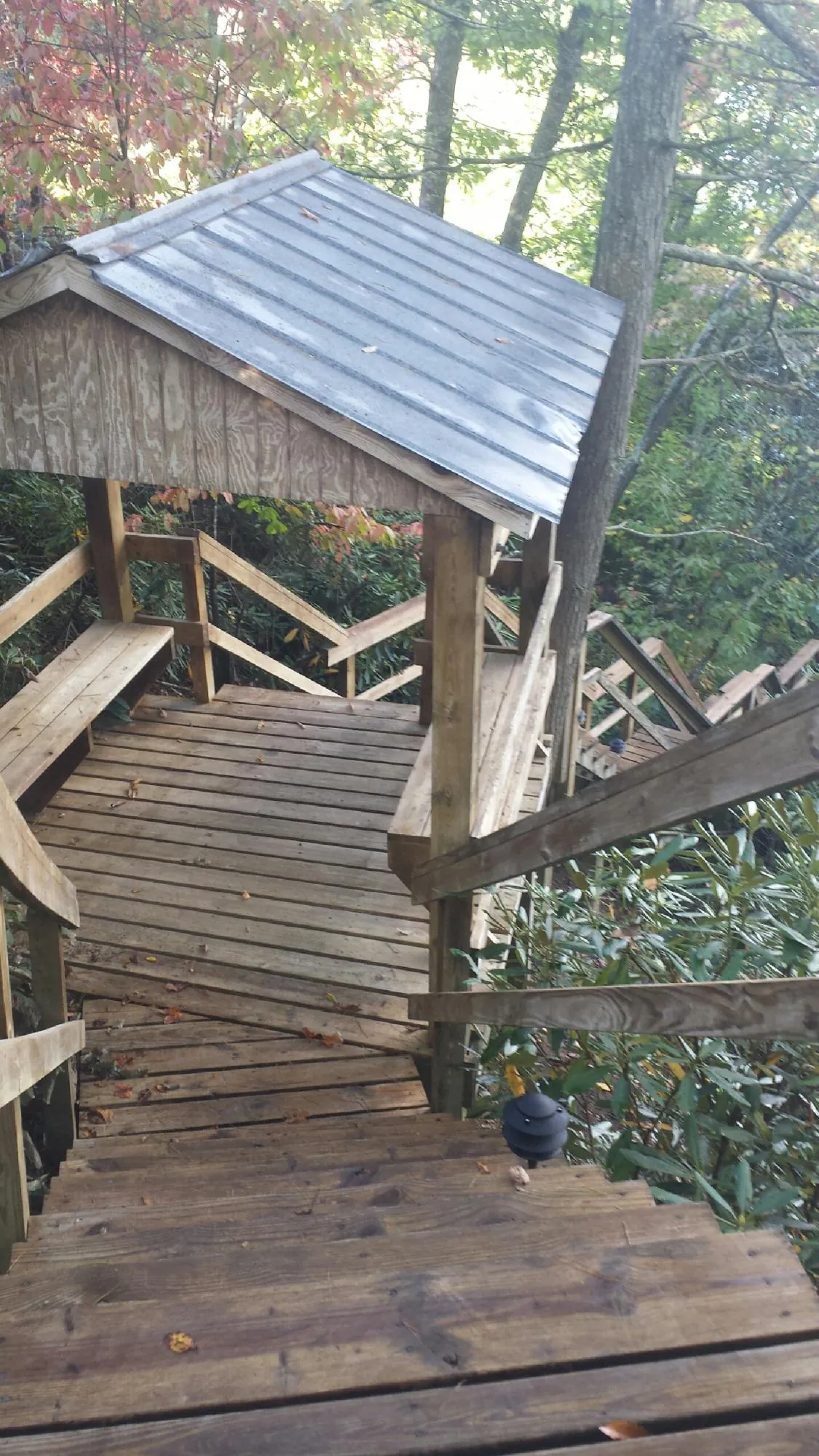 Metal roofed shelter over wooden steps on a wooded walkway — Skylight Repair & Installation work by our crew in Blairs