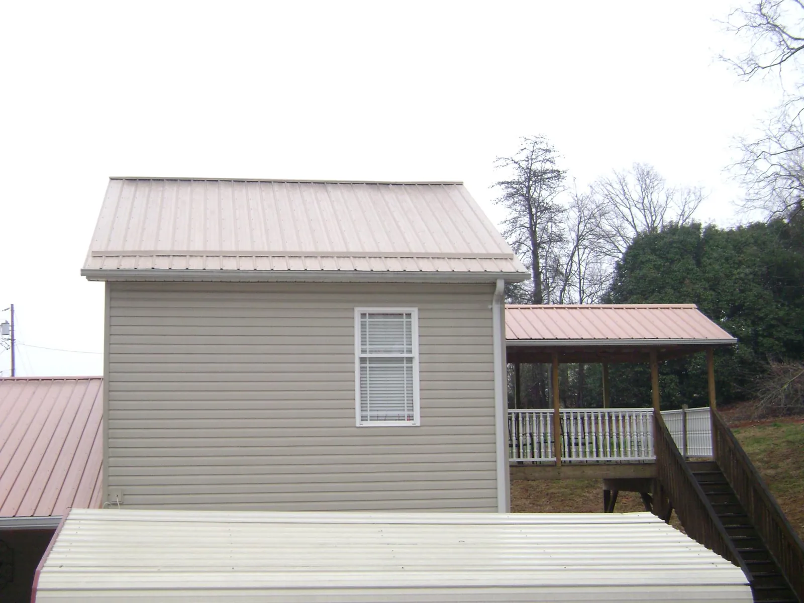 Tan metal roofs on a two story addition and attached porch, from a Roof Replacement job in Blairs